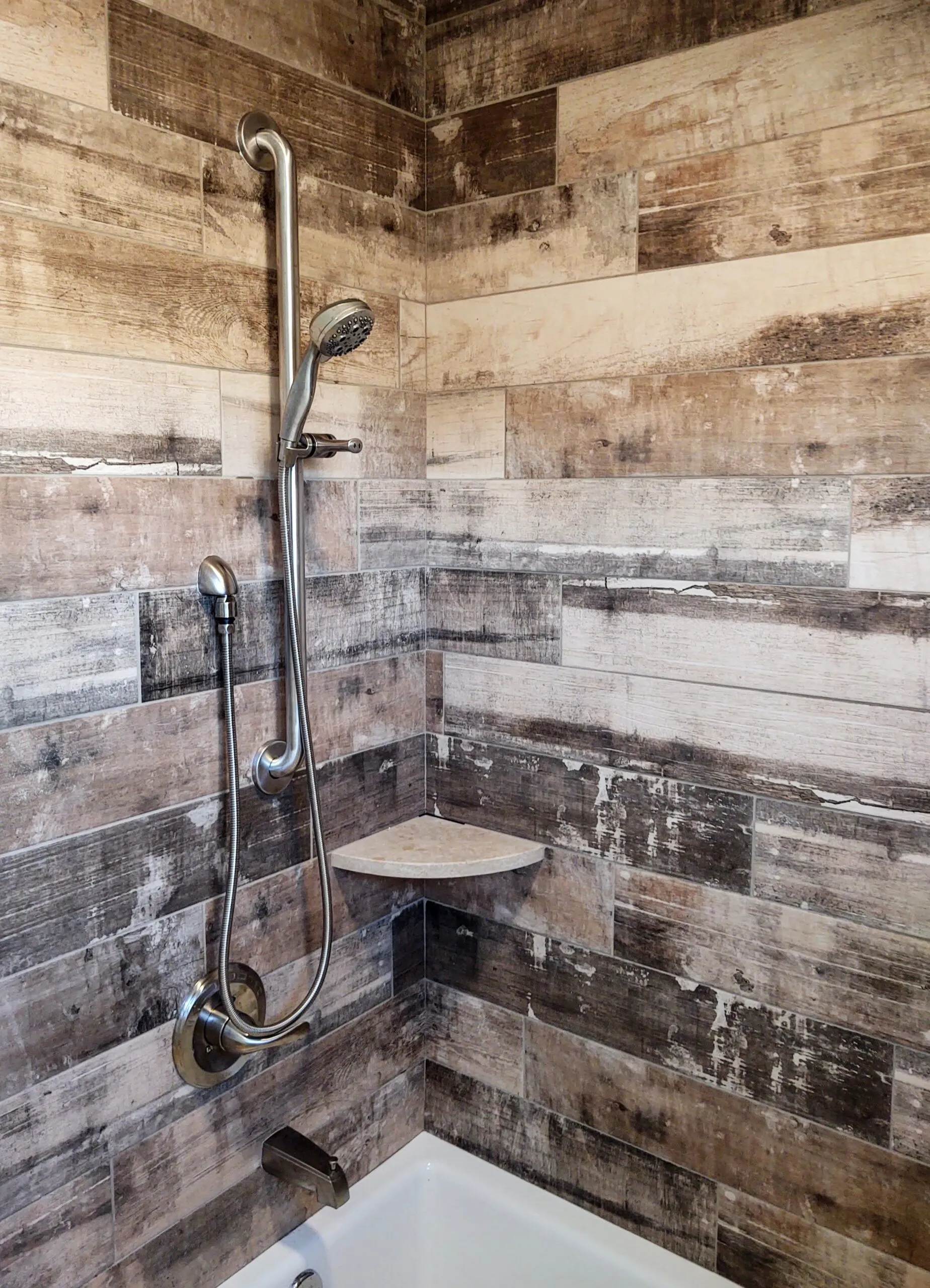 Walk-in shower tiled in reclaimed wood look plank with a corner seat